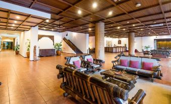 a spacious living room with wooden furniture , including chairs and a couch , arranged around a coffee table at Hotel Timor