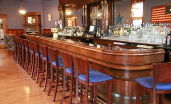 a wooden bar with a row of chairs and a wine glass on the counter at The Hotel Belvidere