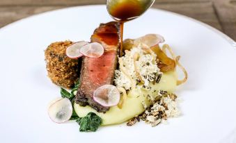 a white plate with a variety of food items , including meat , vegetables , and sauce , placed on a dining table at The Selsey Arms