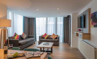 a modern living room with gray couches , wooden floors , and large windows that offer views of the city at Talbot Hotel Wexford