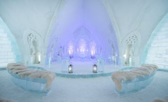 a large , white room with a blue light shining through the center is shown in this image at Hotel de Glace (Ice Hotel)