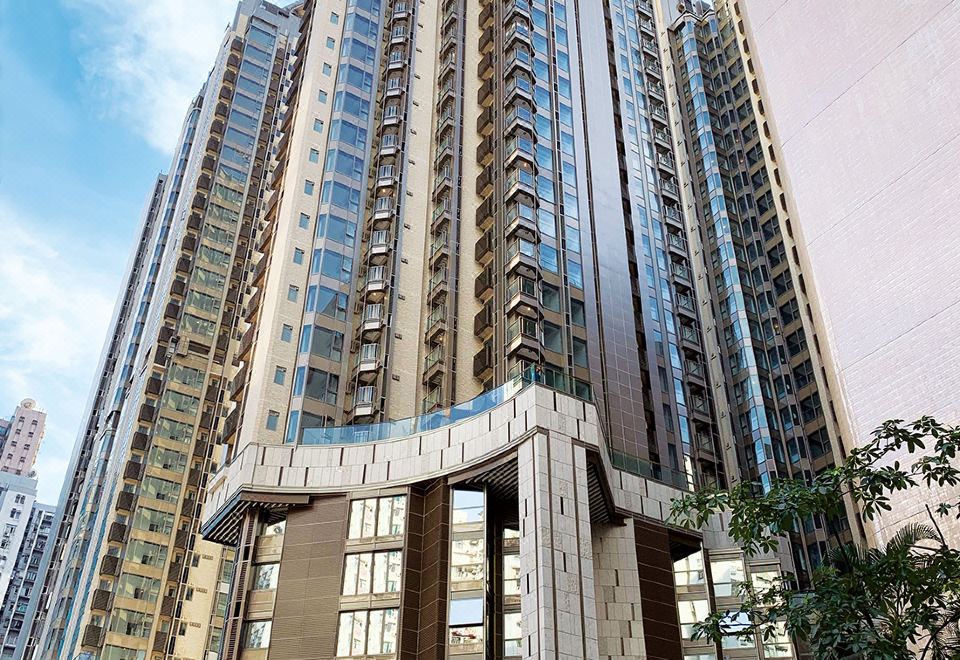 In front of an apartment complex stands a tall building with numerous windows on its side at Hotel Alexandra