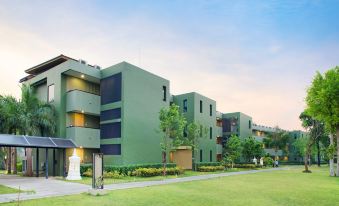 a modern apartment building with multiple balconies and greenery , surrounded by trees and a clear blue sky at Mida Resort Kanchanaburi