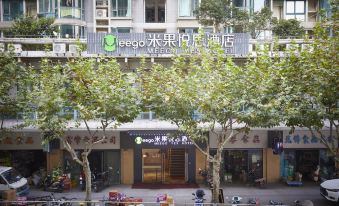 A large building with people walking in front and trees lining the sidewalk beside it at Meego Yes Hotel