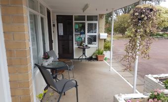 a small apartment with a balcony , outdoor furniture , and potted plants , providing a comfortable living space at Emu Point Motel