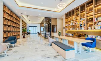 a modern lobby with a marble floor , wooden shelves filled with books , and a seating area at Atour Hotel