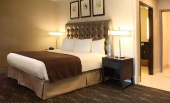 a hotel room with a large bed in the center of the room , surrounded by various pieces of furniture and decorations at DoubleTree by Hilton Claremont