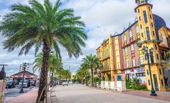 a street view of a colorful building with palm trees and people walking on the sidewalk at Sunset Beach Hotel