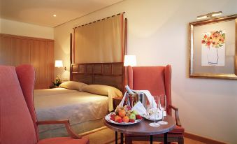 a hotel room with a bed , two chairs , and a table filled with food on it at Parador de Salamanca