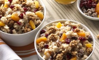 a dining table with two bowls of oatmeal on it , each filled with various ingredients at Home2 Suites by Hilton Middletown