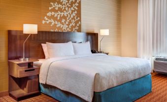 a large bed with white sheets and a blue skirt is in a hotel room at Fairfield by Marriott San Salvador