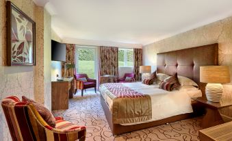 a luxurious hotel room with a large bed , multiple chairs , and windows that offer views of the outside at Grosvenor Pulford Hotel & Spa