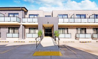 a modern apartment building with a set of stairs leading up to the entrance , surrounded by lush greenery at ValueSuites Penrith