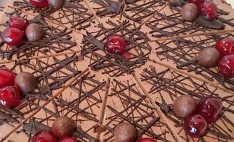 a chocolate cake with cherries and chocolate drizzle is displayed on a white plate , ready to be served at LUDWIGS