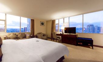 The room is furnished like an apartment and includes large windows, a bed, and a desk in the middle at UChoice Hotel