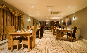 a large dining room with wooden tables and chairs arranged for a group of people to enjoy a meal together at The Britannia Inn & Waves Restaurant