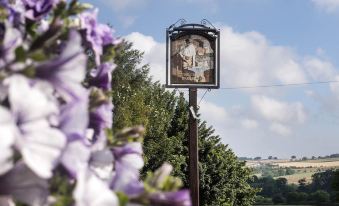 a large wooden sign with a painting of a man is seen in the background at The Cook and Barker Inn