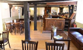 a spacious , well - lit restaurant with wooden furniture , including tables and chairs , and a bar area at The Hollies Inn