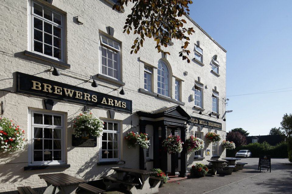"a brick building with a sign that says "" the old anchor "" on it , surrounded by trees" at The Brewers Arms