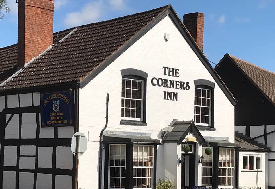 "a white and black pub with a sign that says "" the corners inn "" in front of it" at The Corners Inn