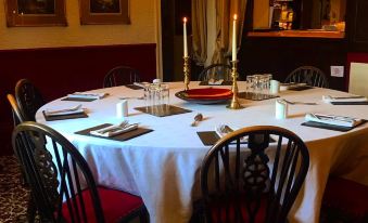 a large round table with white tablecloth and red chairs , set for a formal dinner at St Quintin Arms