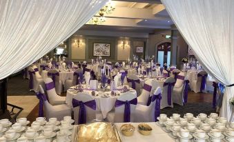 a large banquet hall filled with tables and chairs , ready for a wedding reception or other event at Ballymac Hotel