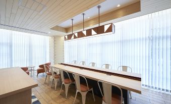 contains a conference room with long tables and chairs in the middle, as well as an adjacent office at Sotetsu Fresa Inn Osaka Namba