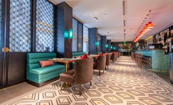 The large, modern-looking room contains tables and chairs, serving as both a lobby and a restaurant at Jinjiang Metropolo Shanghai Xintiandi Hotel