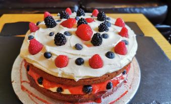 a large , layered cake with berries and whipped cream is sitting on a dining table at Three Wheat Heads