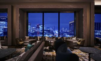 a modern living room with large windows offering a view of the city at night , including comfortable couches and chairs at The Royal Park Hotel Iconic Osaka Midosuji