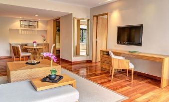 a modern living room with hardwood floors , a large flat - screen tv mounted on the wall , and a dining area at The Taaras Beach & Spa Resort