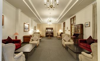 a large , well - lit room with multiple couches and chairs arranged in a sitting area , creating a cozy atmosphere at Galle Face Hotel