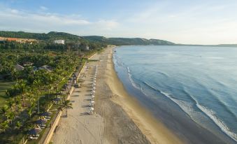 aerial view of a beautiful beach with white sand , clear blue water , and numerous people enjoying the sunny day at Pandanus Resort