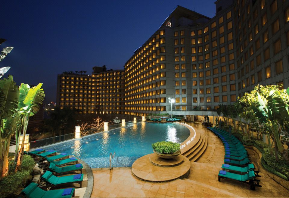 A hotel with a lit-up pool in the center, surrounded by illuminated buildings at Harbour Plaza Metropolis