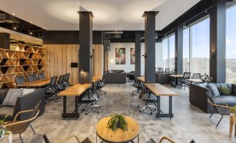 a modern office space with wooden tables and chairs , surrounded by large windows and black walls at Sage Melbourne Ringwood