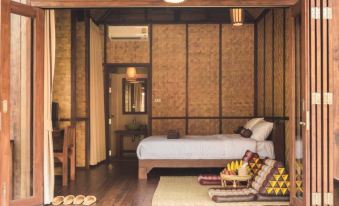a cozy bedroom with a bed , wooden walls , and a rug on the floor , next to a dining area with chairs at Azalea Village