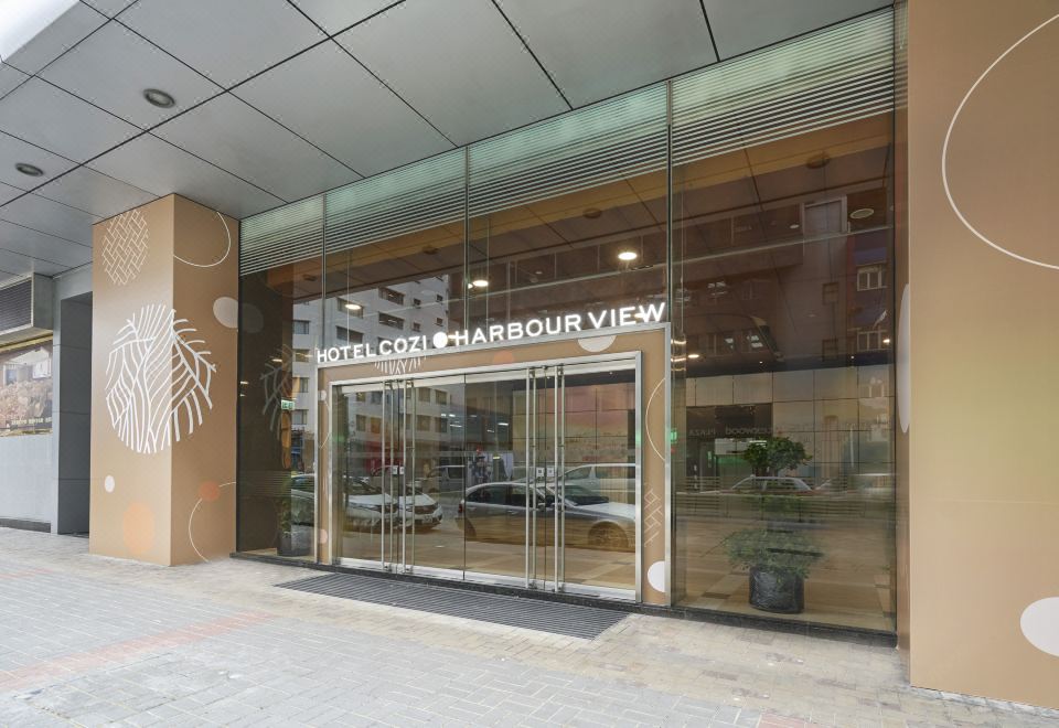 The store front features an entrance with an American flag displayed in its glass and metal frame at Hotel COZI Harbour View