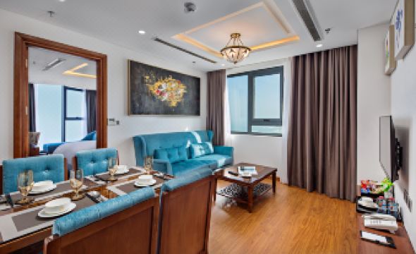a modern living room with blue sofas , wooden furniture , and a large painting on the wall at Paris Deli Danang Beach Hotel