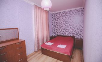 a bedroom with a wooden floor , a pink bed with two towels on it , and a dresser at Veranda