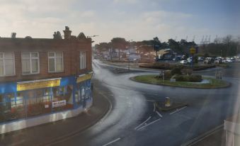 a view from a window shows a street with buildings , cars , and trees on the right side at Premier Inn Felixstowe Town Centre