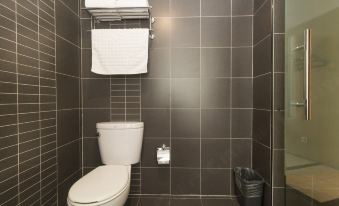 The bathroom features a white toilet and grey tiled walls, adjacent to a black shower stall at Ruizhao Hotel (Beijing Guomao)