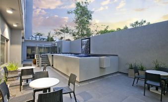 a modern outdoor space with a white table , chairs , and an outdoor fountain , surrounded by greenery at Argus Hotel Darwin