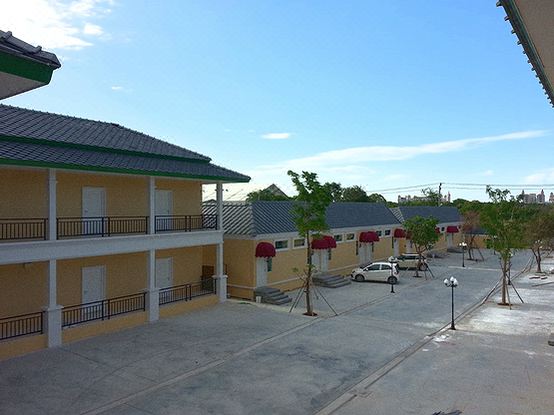 a row of buildings with a car parked in front and trees on the side at Pudis Ville