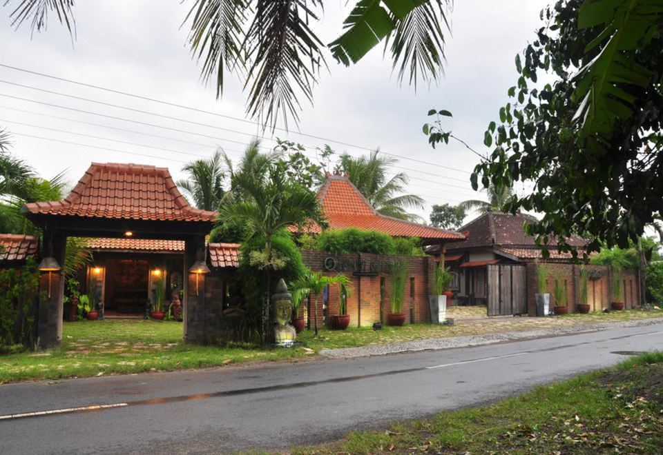 a street view of a small town with houses and palm trees , along with a road running through it at Astuti Gallery Homestay