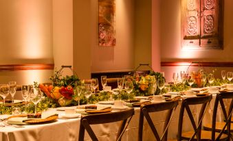 a long dining table set with wine glasses , plates , and utensils , ready for a meal at Juniper Hotel Cupertino, Curio Collection by Hilton