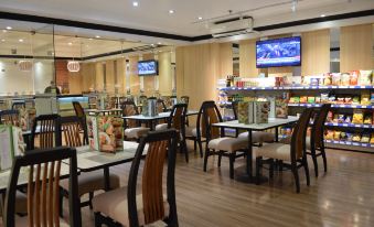 a restaurant with multiple tables and chairs , a bar area , and large televisions mounted on the wall at Executive Hotel