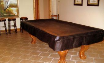 a large wooden pool table with a black tablecloth covering it , surrounded by chairs and a doorway at Mountain Cove Farms Resort