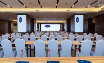 A spacious conference or meeting room arranged with tables and chairs for an event at Hampton by Hilton Ji'an