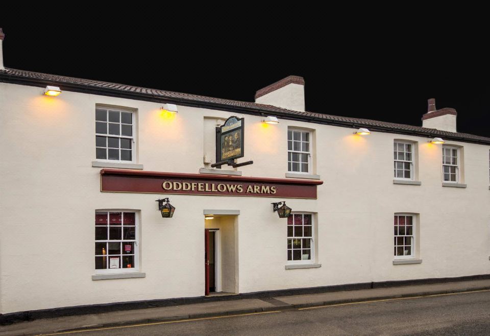 the exterior of a pub called oddfellows arms , which is illuminated by the night sky at The Oddfellows Arms