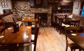 a dining room with wooden tables and chairs , a fireplace , and a dartboard on the wall at The Engine Inn